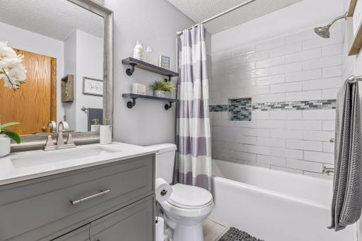 Updated full bathroom with a stylish gray vanity, modern finishes, and relaxing tub/shower combo.