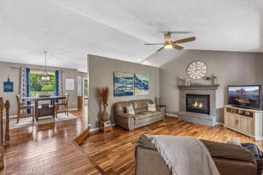 Spacious living room featuring a cozy gas fireplace, rich hardwood floors, and vaulted ceilings.