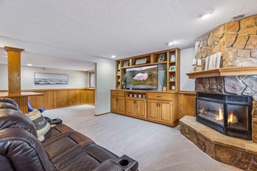 Lower-level entertainment space with a stone gas fireplace and custom built-ins.