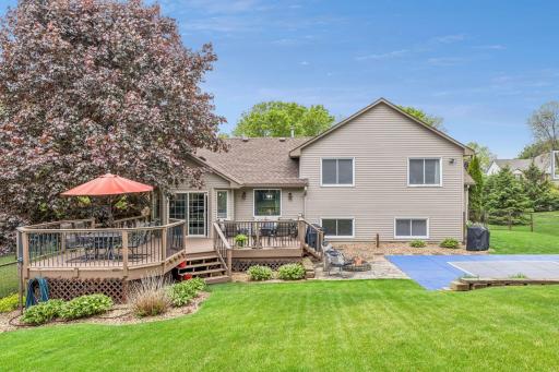 Expansive fenced backyard featuring a large two-tier deck, fire pit, and basketball court.