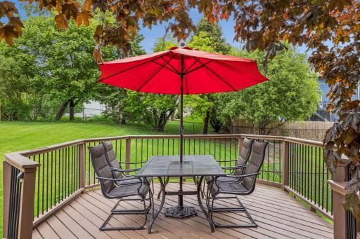 Relaxing deck seating area with comfortable furniture and a bright red umbrella.