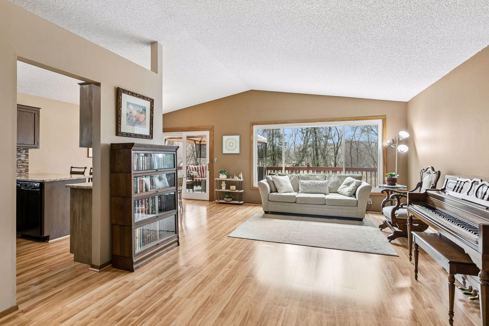 Main floor living room is warm & inviting with vaulted ceilings and a spacious floorplan. Beautiful views of the private backyard are captured with the wall of windows.