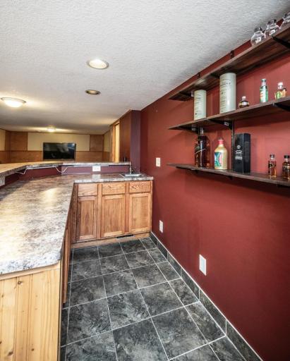 Behind the wet bar. Refrigerator, bar stools and shelves are included.