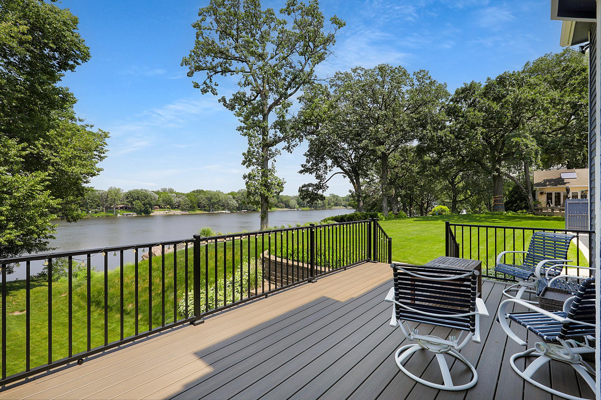 The cedar-cladded sunroom features large windows overlooking the river, vaulted ceilings, and walks out to the maintenance free deck.