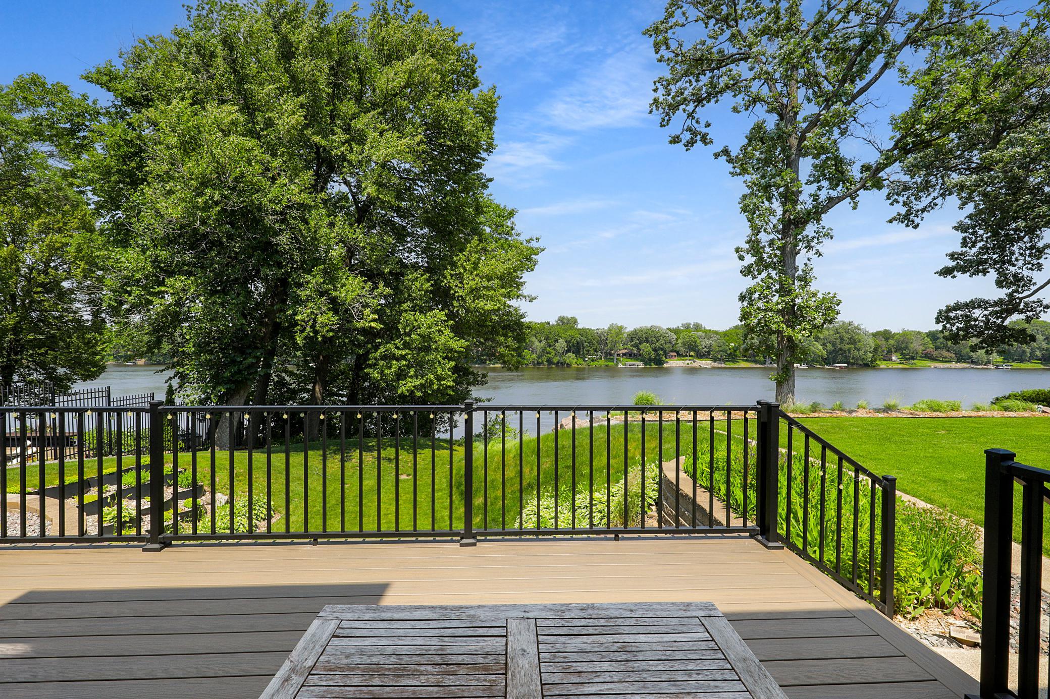 The cedar-cladded sunroom features large windows overlooking the river, vaulted ceilings, and walks out to the maintenance free deck.