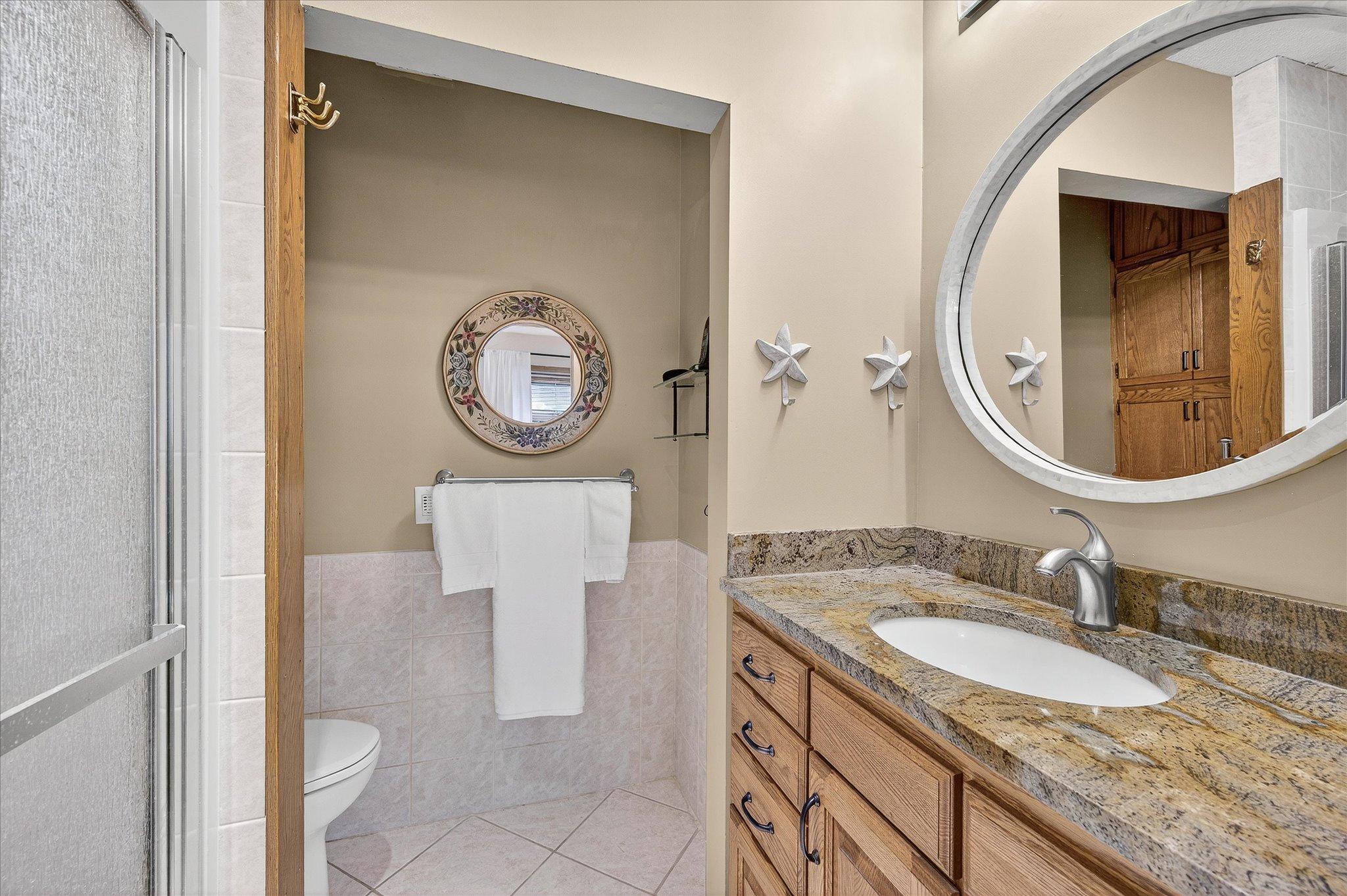 Custom cabinets with granite countertop and more storage above the toilet.
