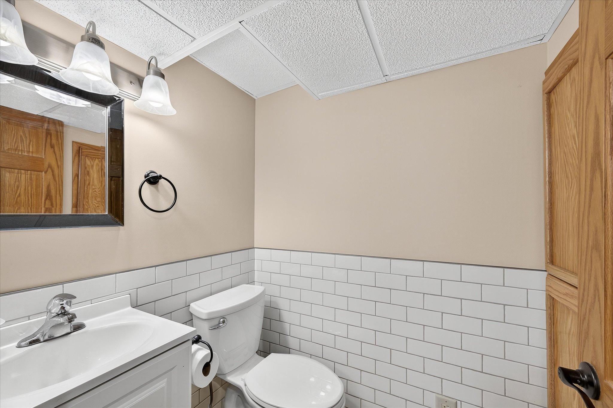 Half Bathroom on lowest level with new tile walls, floors and cabinets.