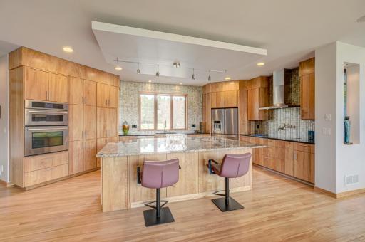 The chefâs kitchen is both functional and beautifully appointed, featuring custom cabinetry, granite countertops, stainless steel appliances, an oversized center island, and a textured tile backsplash.