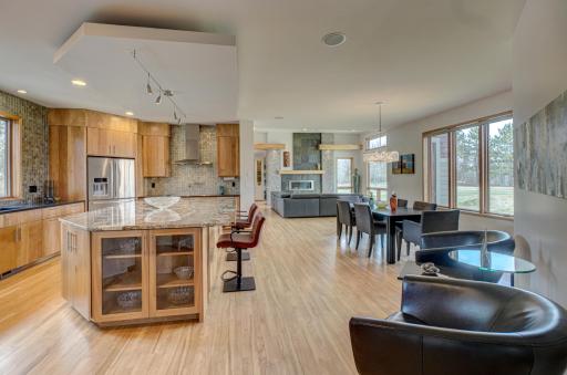 Inside, the layout opens with soaring ceilings, rich wood floors, and a natural flow between the kitchen, dining, and living spaces. Built-in speakers are integrated throughout the home, inside and out, elevating the atmosphere throughout the home.