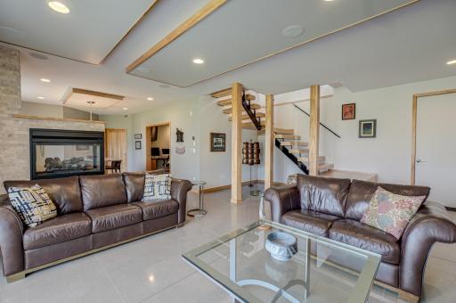 The walkout lower level is built for entertaining and flexibility, featuring heated floors, a double-sided fireplace, a full bar and kitchen ideal for guests or extended stays, and access to a custom-designed concrete patio.