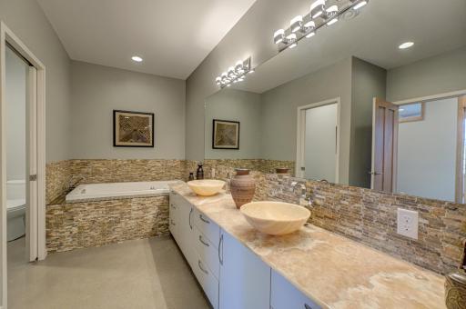 A spa-inspired bathroom with sauna, soaking tub, and custom lighting creates a true in-home retreat.