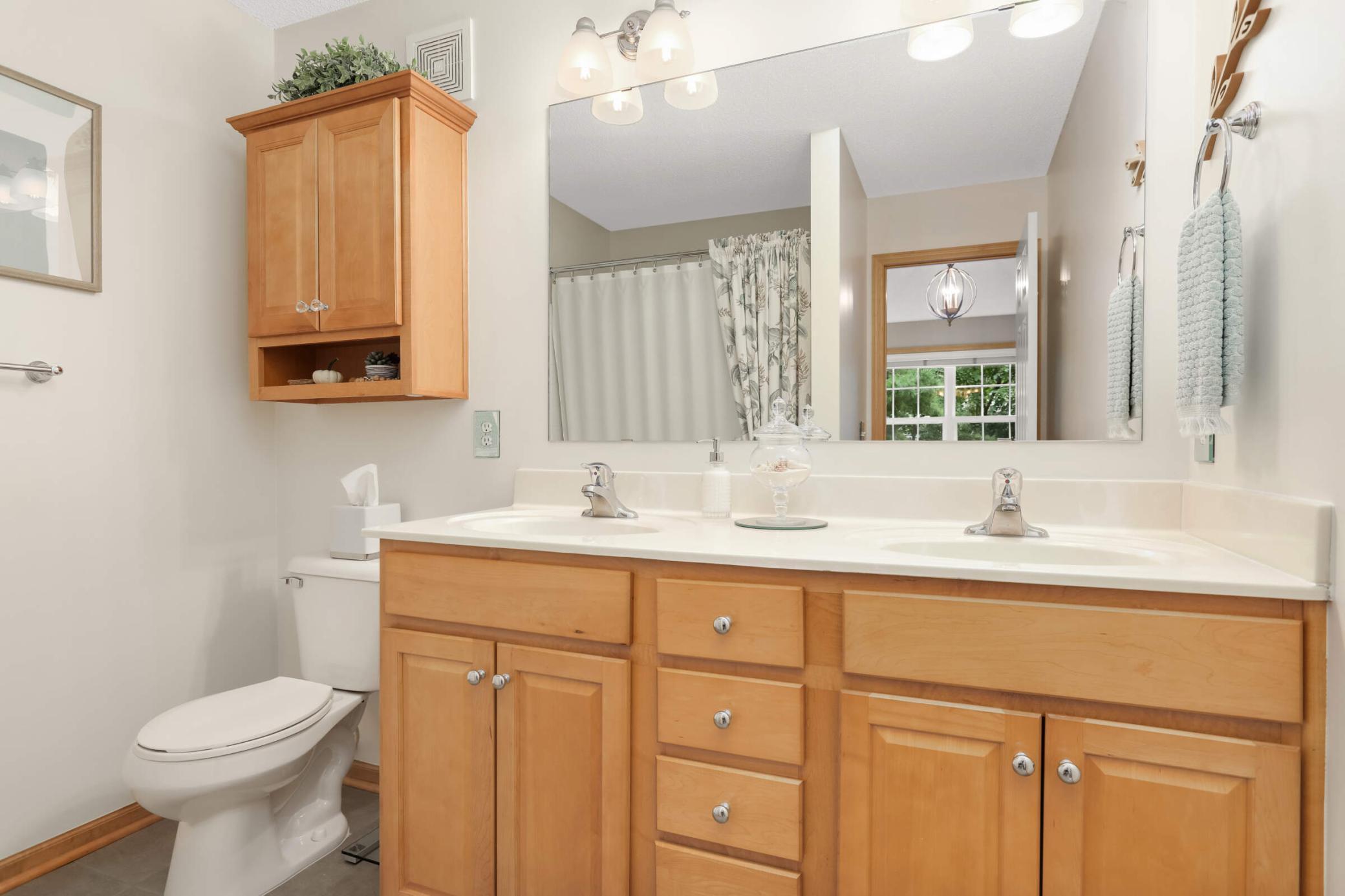 The private primary bathroom is nicely finished with maple cabinetry and dual sinks, creating a comfortable and well-appointed retreat.