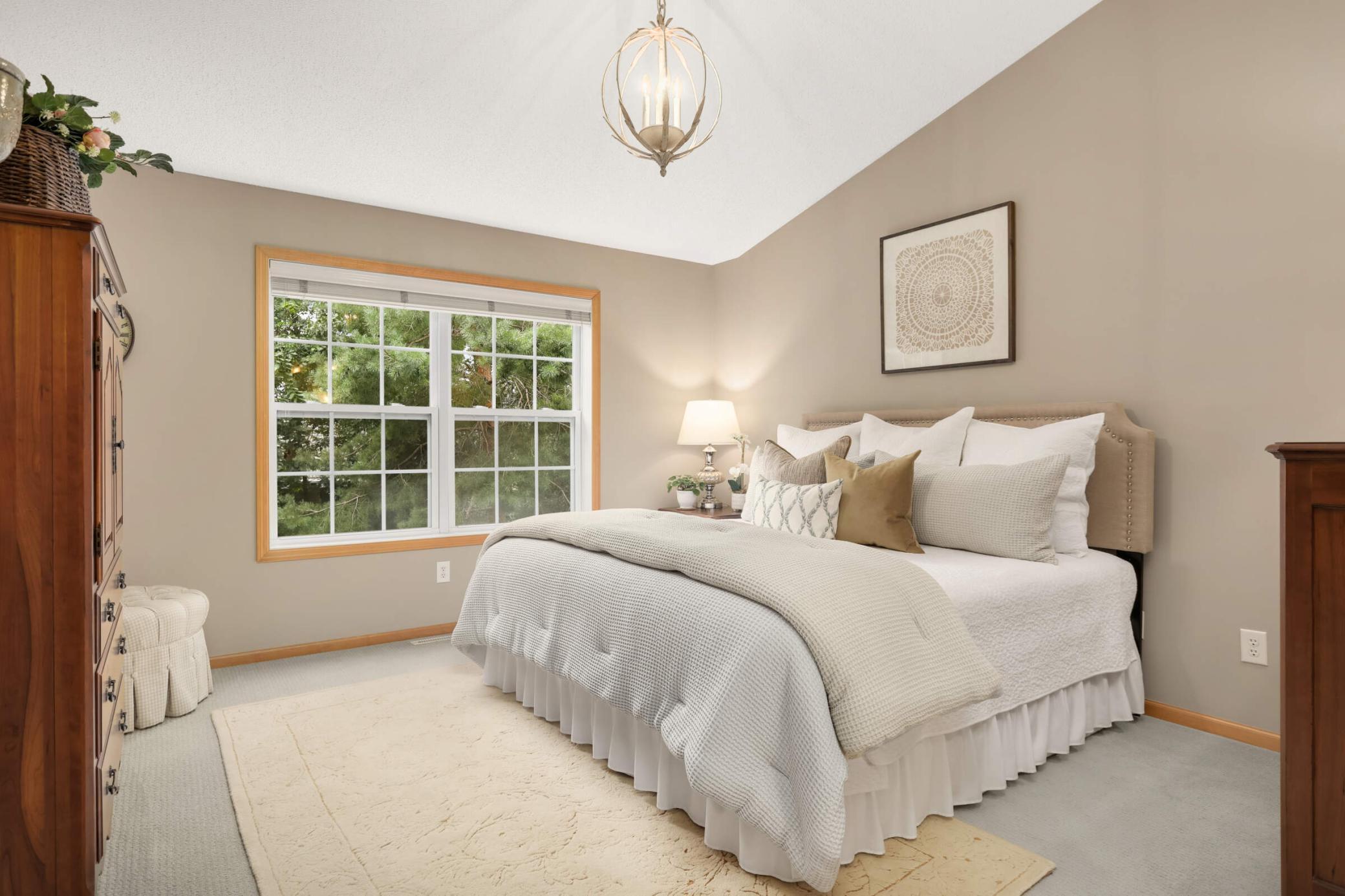 Spacious primary suite featuring a beautiful vaulted ceiling, large walk-in closet, private primary full bathroom and a peaceful tree-lined view.