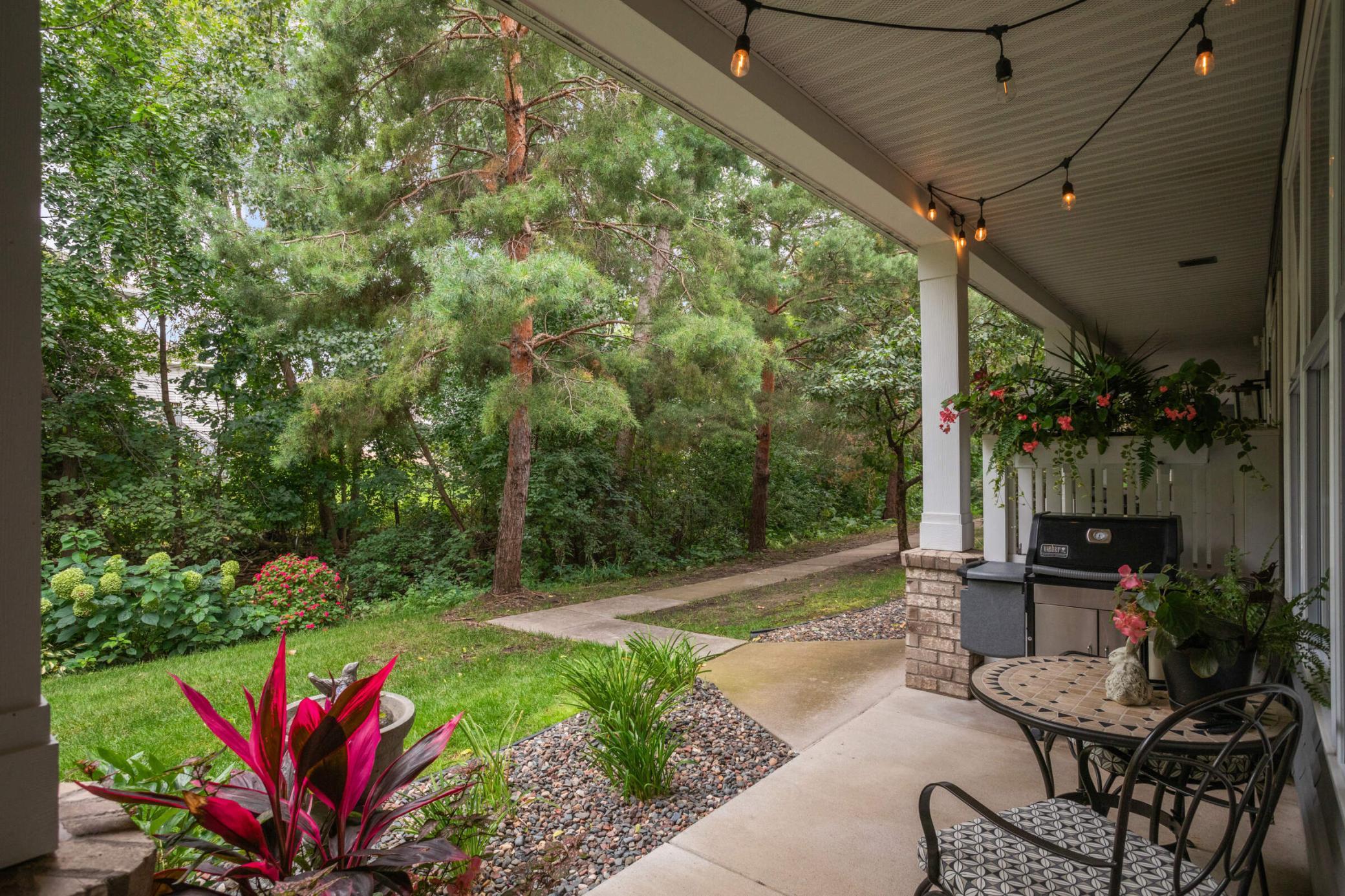 Turnkey, exceptionally cared for townhome with a desirable floor plan. Covered porch featuring mature trees and a colorful display of well maintained flowers, creating a vibrant and welcoming outdoor space.