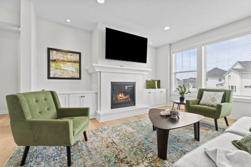 Stylish main level living room with custom built in cabinetry, gas fireplace and accent lighting and a lovely wall of windows filling the home with natural light.