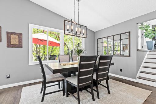 Natural light pours through oversized windows framing the deck outside, while a stunning geometric chandelier anchors the dining space below, warm, bright & completely inviting.