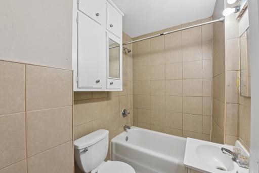 Full bathroom with tiled surround, tub/shower combination, and built-in storage.