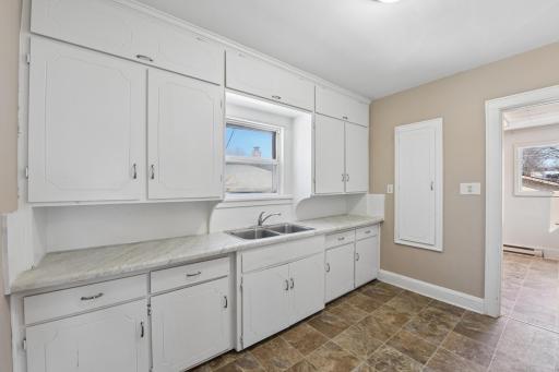 Functional kitchen with ample cabinetry, laminate countertops, and window over sink for natural light.