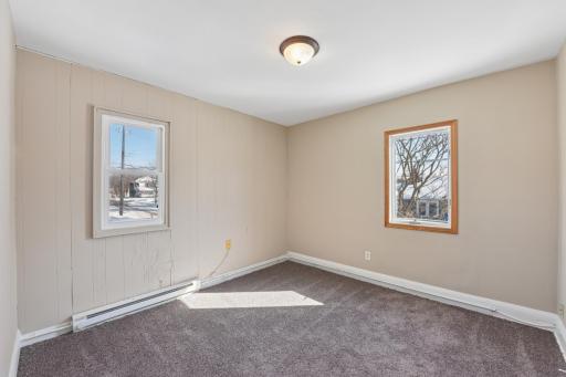 Light-filled bedroom with two windows and neutral finishes, offering a comfortable and functional layout.