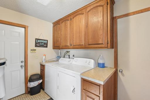 Convenient main-level laundry area with cabinetry, counter space, and utility sink nearby.