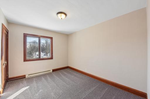 Spacious bedroom with large window, neutral carpet, and classic wood trim.
