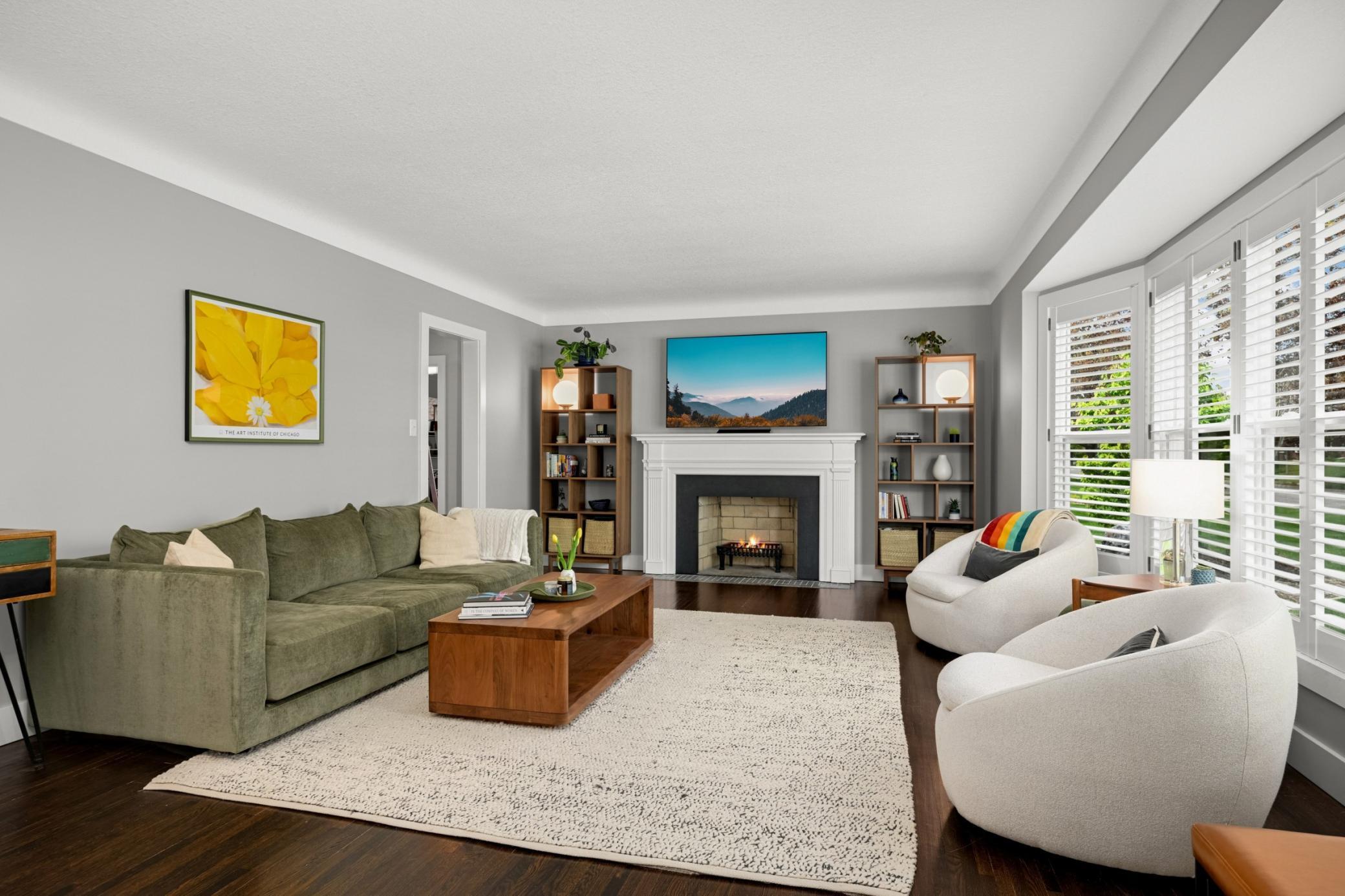 Large living room with bay windows and a wood burning fireplace.