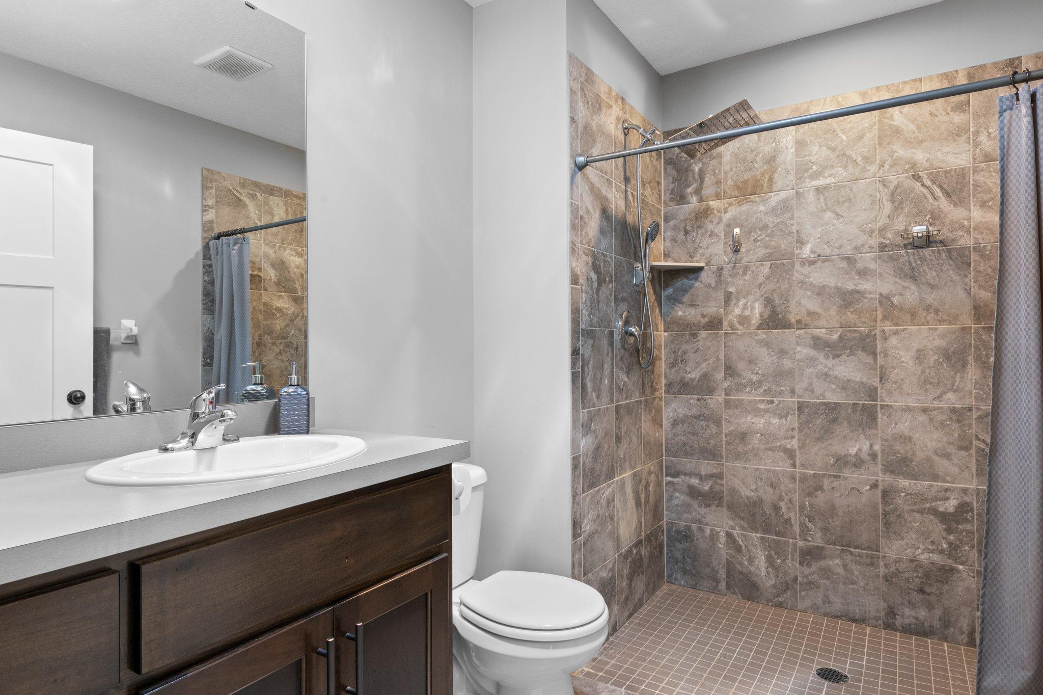 Bathroom has a walk-in or roll in tiled shower with rain showerhead.