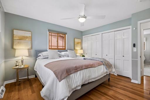 The primary bedroom offers a calm, comfortable retreat with hardwood floors, abundant natural light, and a full wall of closets for exceptional storage