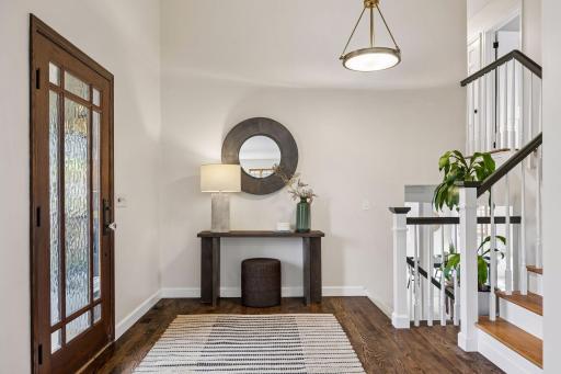The spacious foyer features hardwood floors, a soaring ceiling, and an open staircase connecting multiple levels—creating an airy, connected introduction to the home