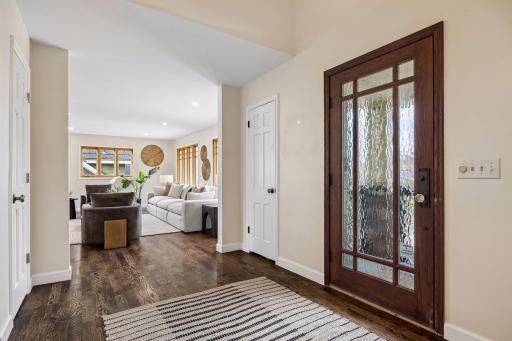 A welcoming covered porch leads to a striking entry, where a glass mission-style door sets the tone for the character and craftsmanship found throughout the home
