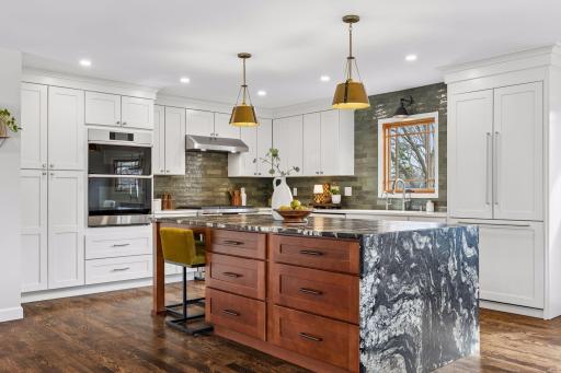 The kitchen makes an immediate impression with a statement center island, featuring a waterfall quartz countertop and abundant storage designed for both everyday use and entertaining