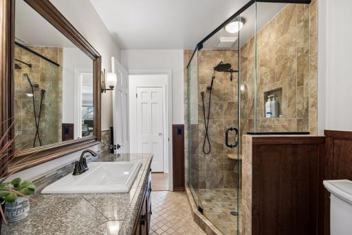 The upper-level bath serves as a walk-through ensuite to the primary bedroom, blending convenience with a clean, modern design