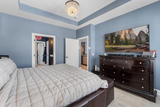 It features a tray ceiling, statement lighting, and a spacious walk-in closet.
