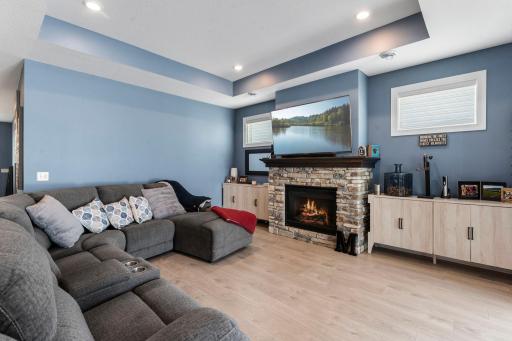 The living room offers a warm and comfortable gathering space with a stone-surround gas fireplace and tray ceiling.
