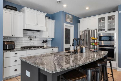 The kitchen is a true centerpiece, featuring stainless steel appliances, a sleek tile backsplash, and walk-in pantry.