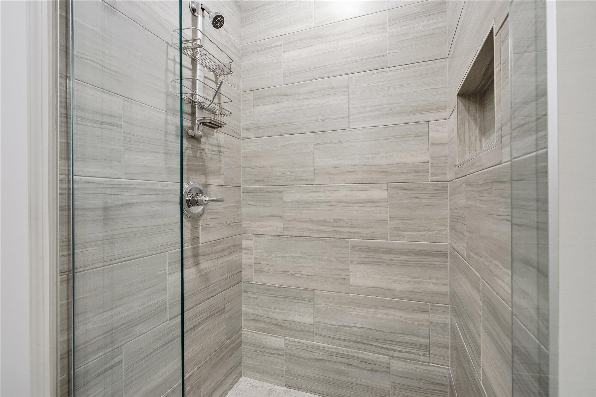 The curbless tiled shower in the primary ensuite is stunning and is part of a beautiful bathroom with a massive double sinks vanity with tiled floors.