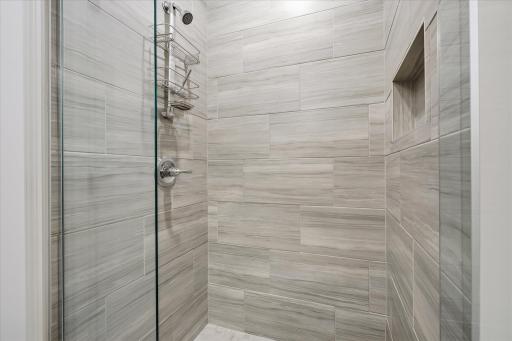 The curbless tiled shower in the primary ensuite is stunning and is part of a beautiful bathroom with a massive double sinks vanity with tiled floors.