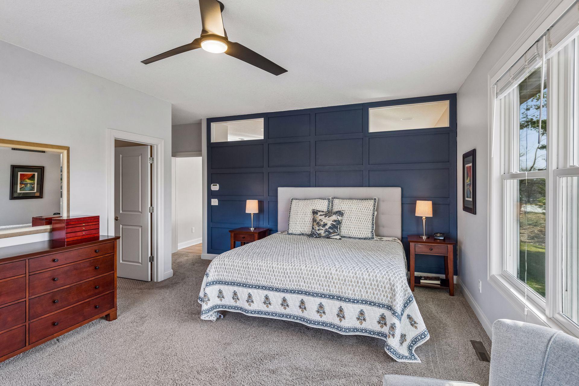 Primary main level en-suite with a decorative wood wall panel and 2 clerestory windows which bring in natural light from the kitchen/living room windows.