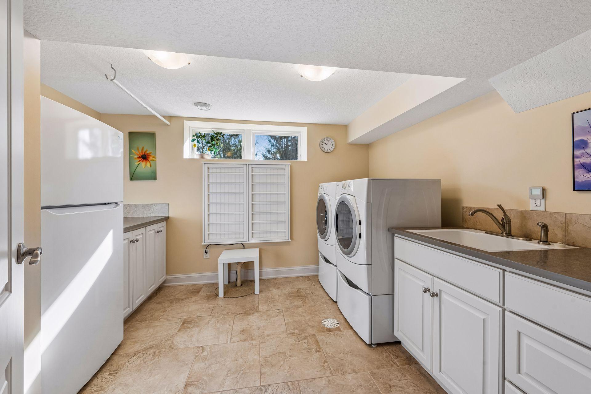 This lower-level laundry room has it all for efficiency! Plus 2 windows let in the morning light!
Washer, dryer, sink, countertops, cabinets, built in drying racks, storage closet and refrigerator #2.