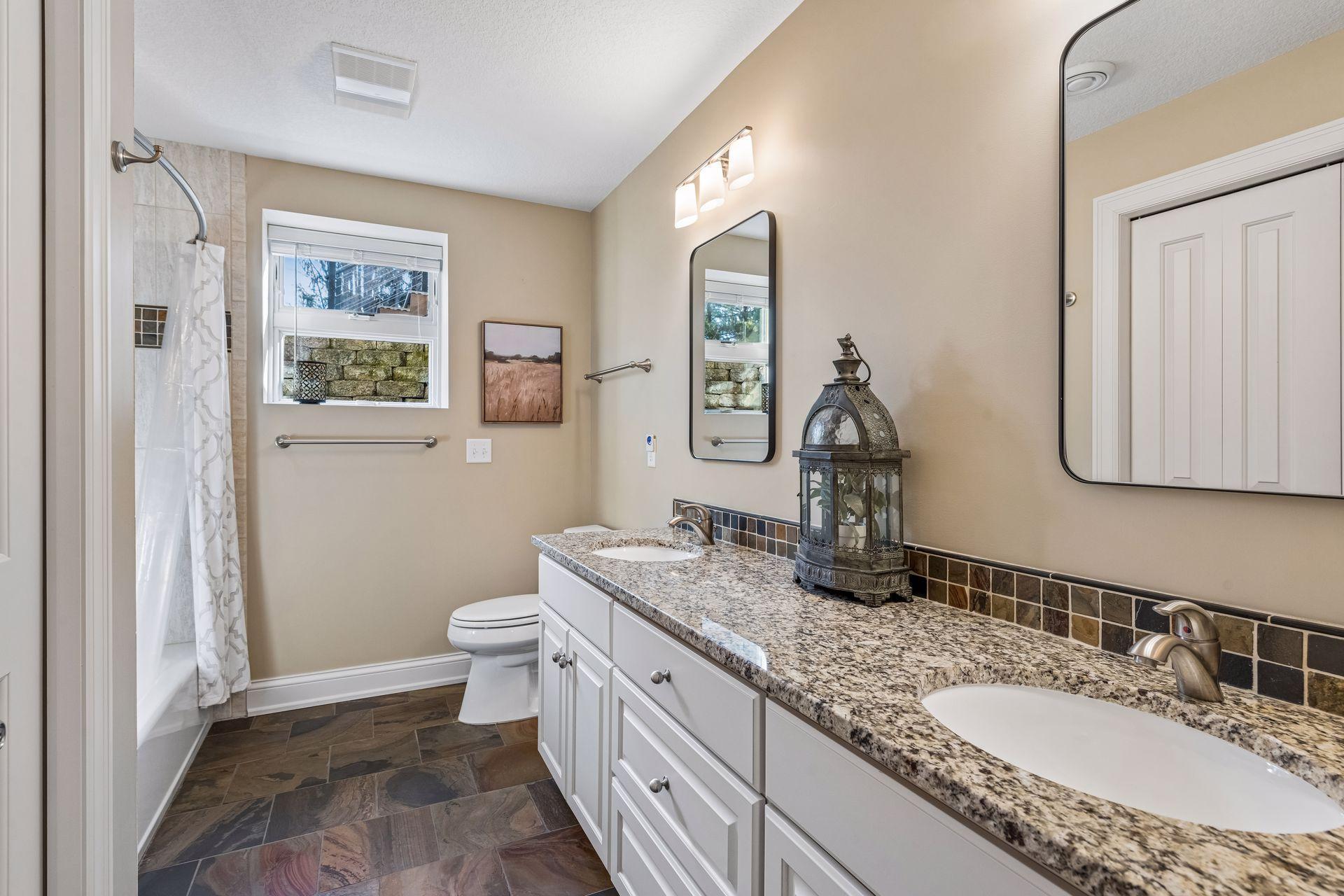 Here is Full Bathroom #3 in the lower level, next to the guest bedroom. Granite countertops, undermount double sinks, backsplash, tile flooring, ceramic tile in shower, and storage closet.