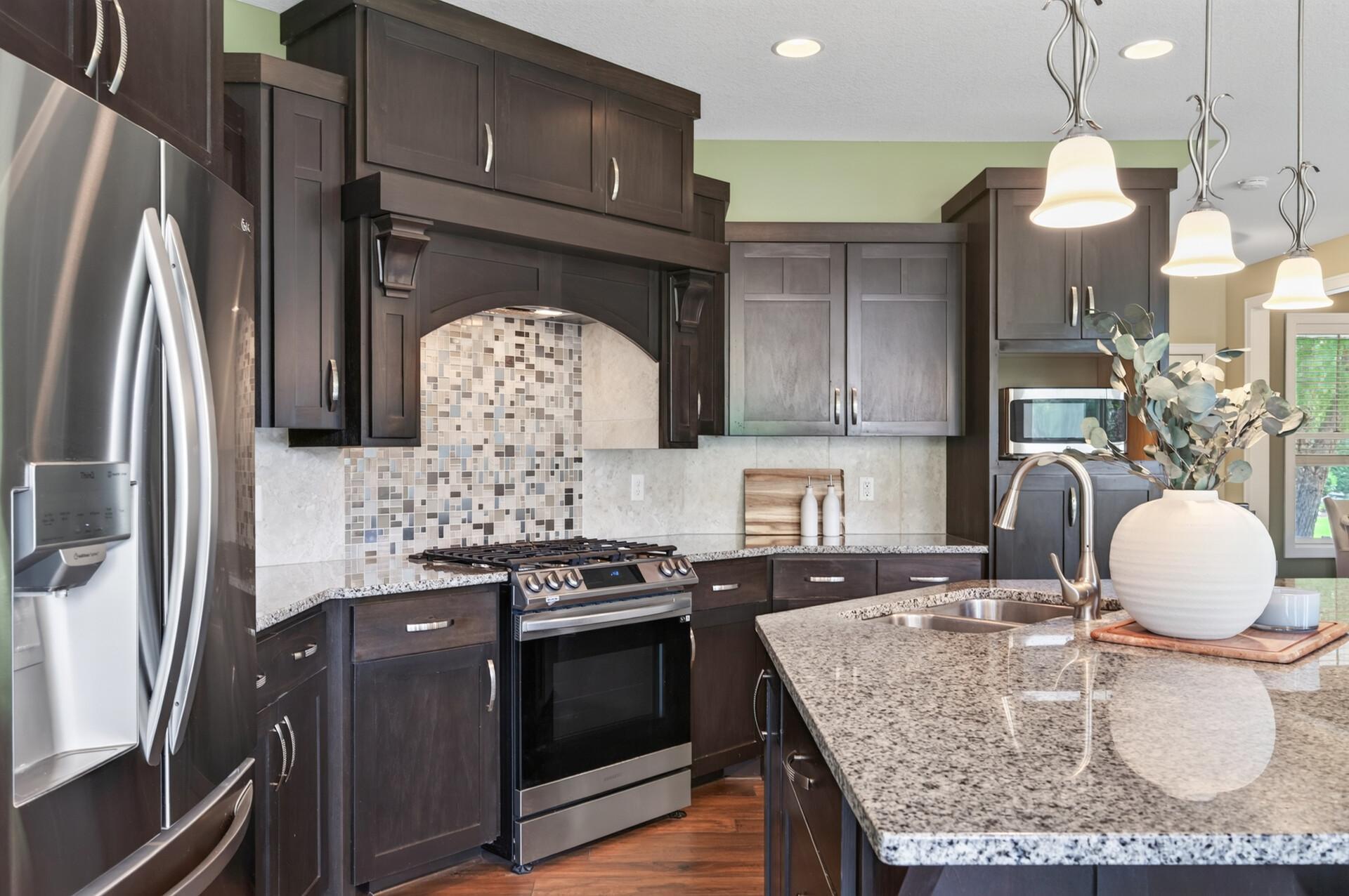 Rich cabinetry, granite countertops, and stainless steel appliances create a timeless kitchen.
