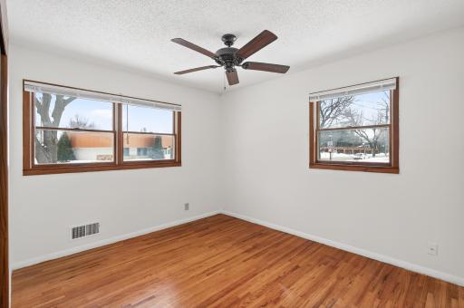 Primary bedroom with hardwood floors and ceiling fan.