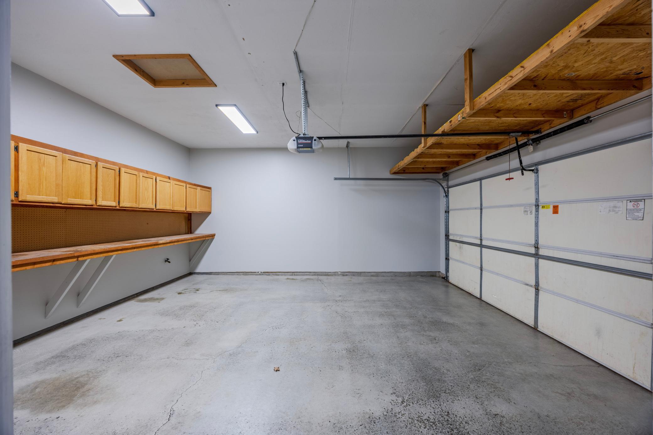 Large garage with built-ins, refreshed floors, and painted walls.
