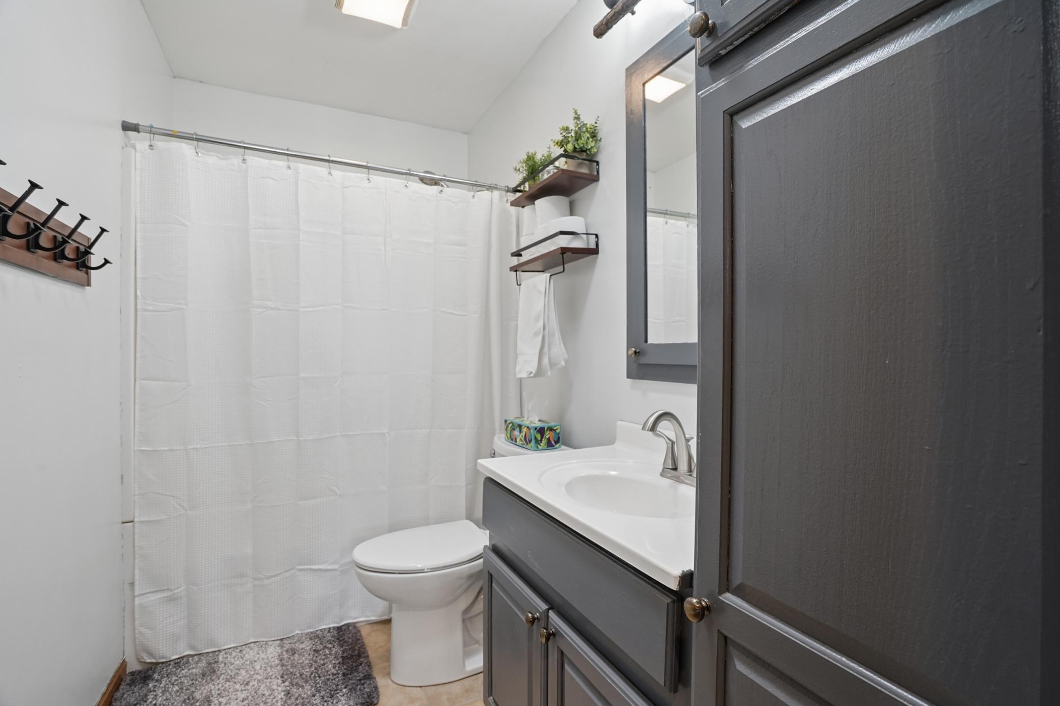 The full main floor bathroom features tile floors and built-in linen storage.