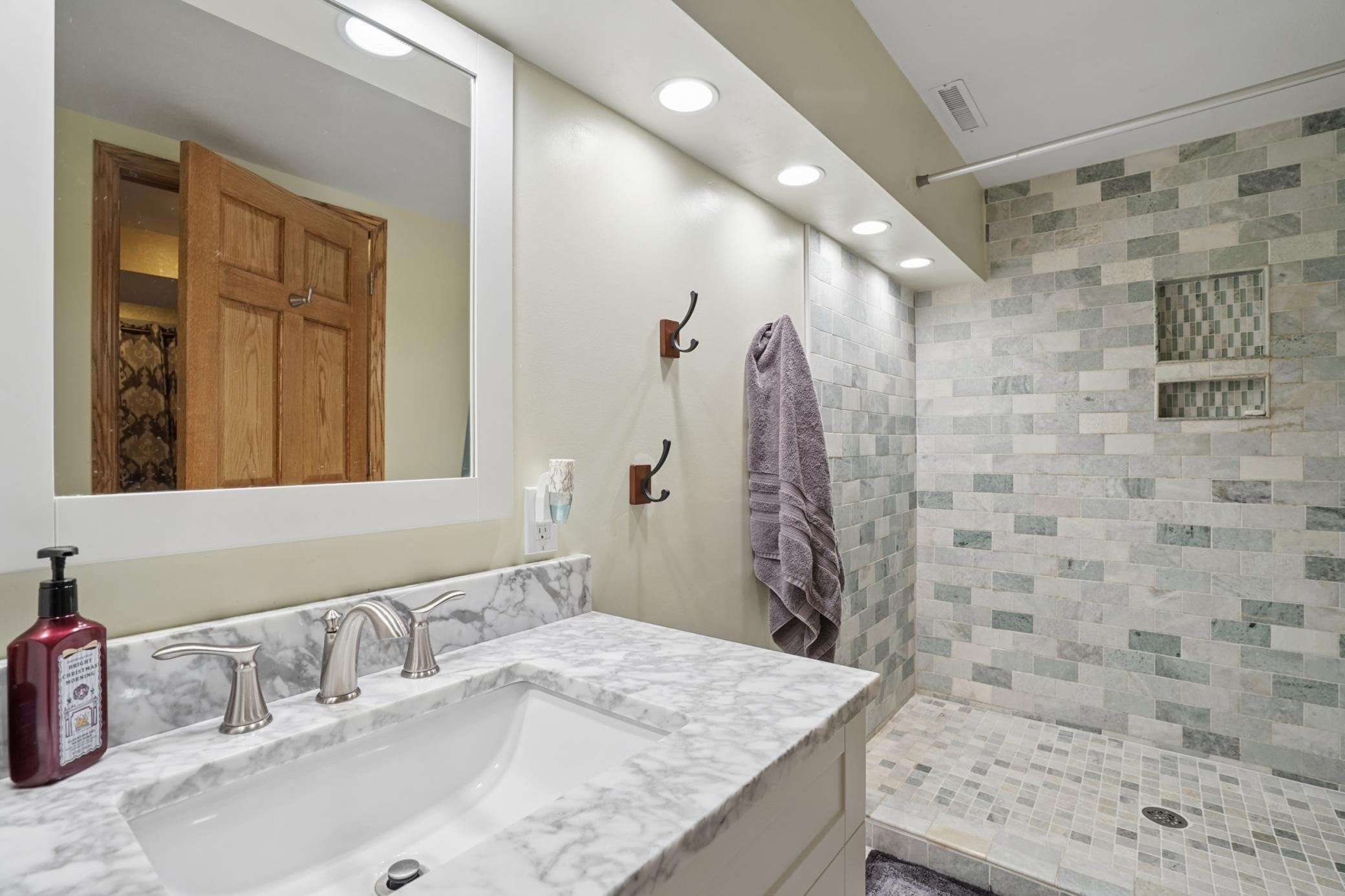 The 3/4 bathroom in the basement features a tiled walk-in shower and a marble countertop.