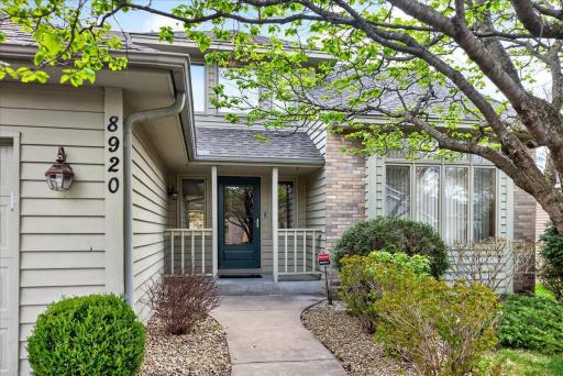 Charming front porch entry with beautifully maintained landscaping.