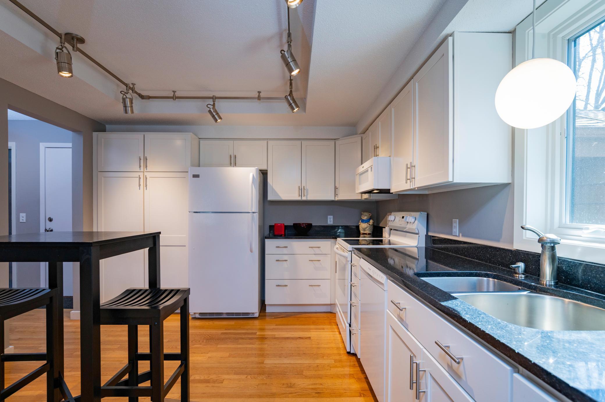 Kitchen has hardwood flooring, large pantry cupboard and ample counter space.