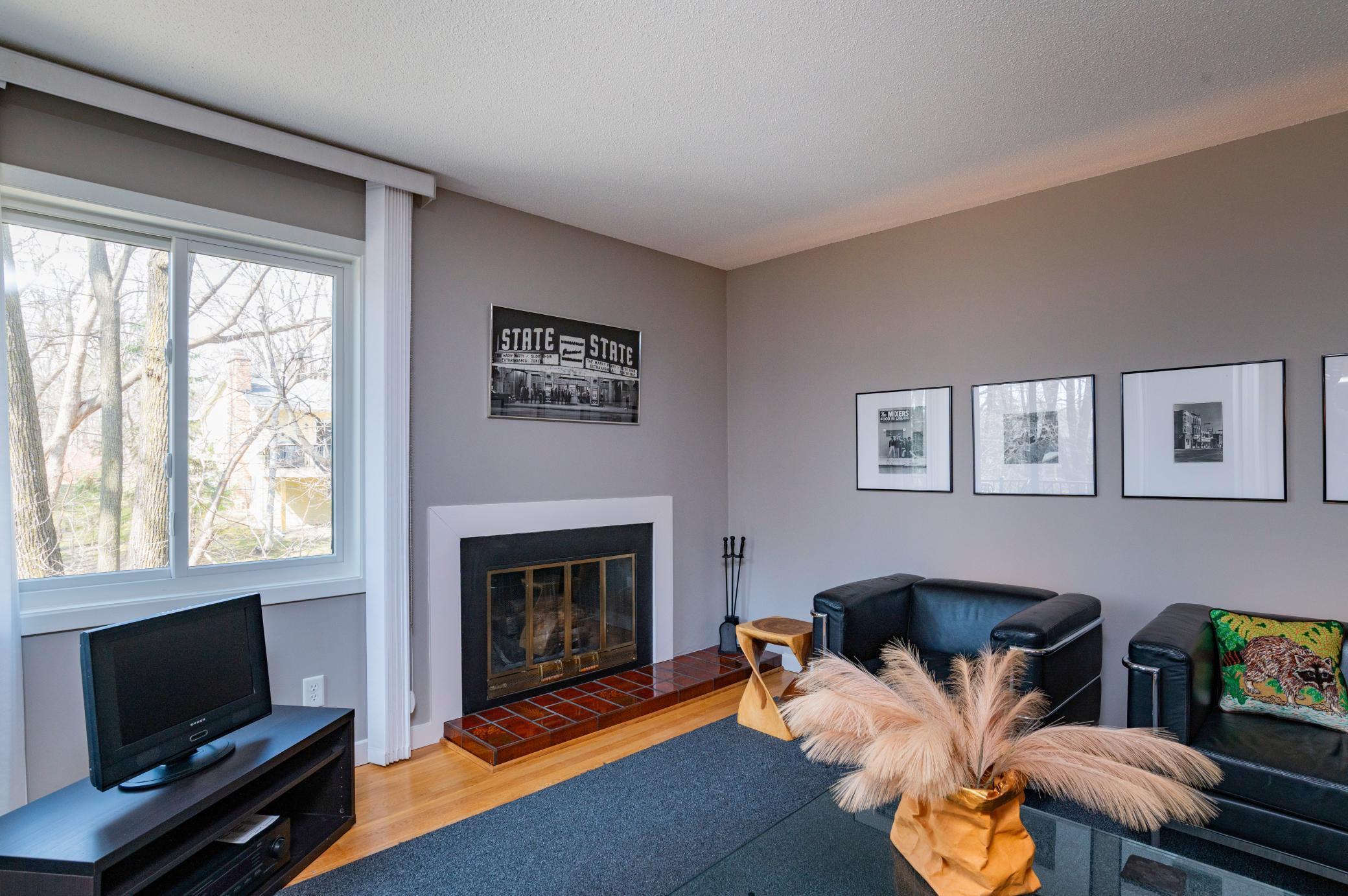 Main floor features hardwood flooring with a spacious Living Room, wood burning fireplace, corner windows and view of wooded backyard and creek bed.