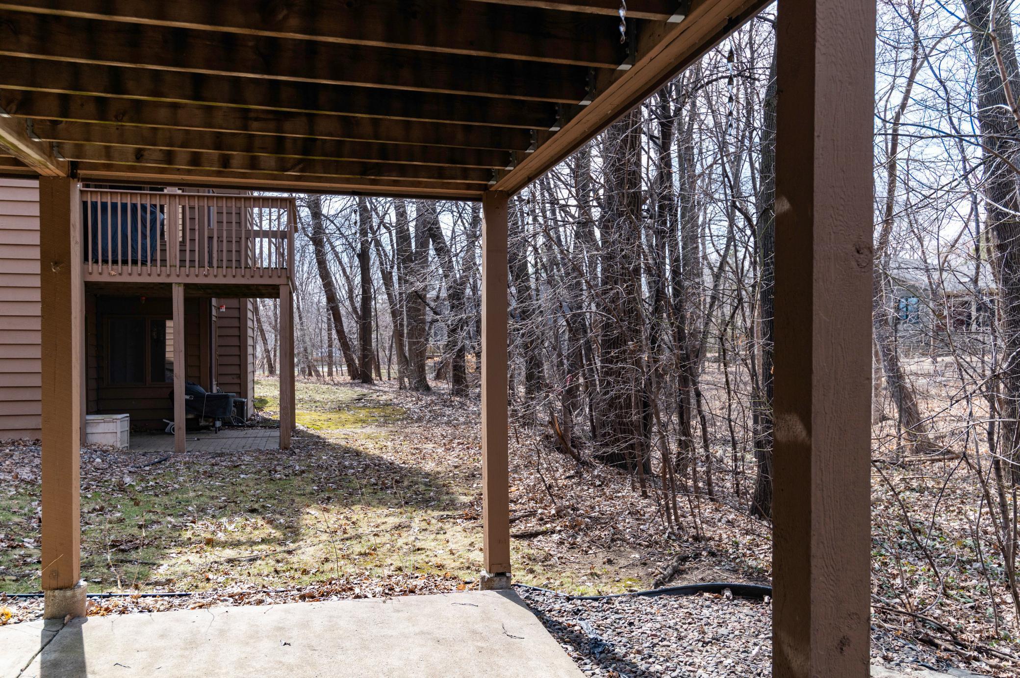 Patio leads to a wooded and private backyard.