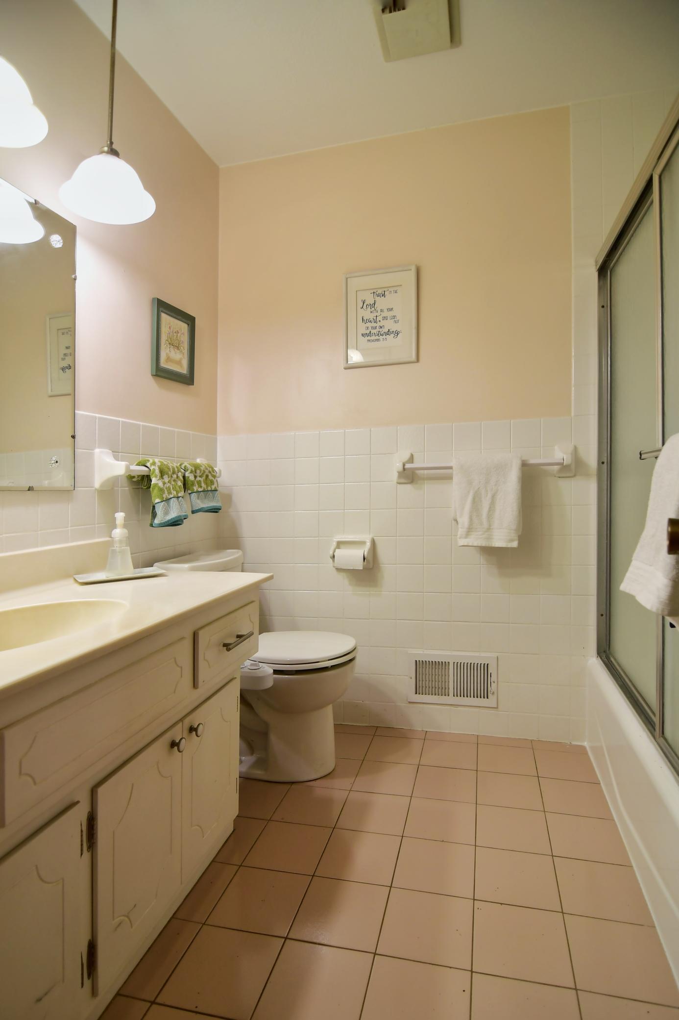 The hallway bath has a tub and shower combination with tile floors.
